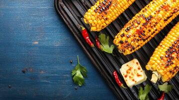 Grilled corn with spices on a rustic pan and blue background. Use culinary concepts photo