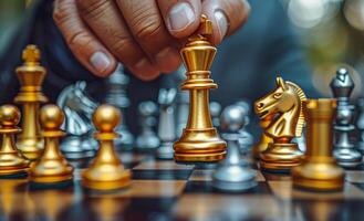 Chess game in progress during afternoon. A hand moves the golden king piece on a chessboard surrounded by various pieces in a park during the afternoon. photo