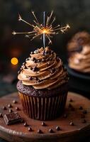 Chocolate cupcake with sparkler on top. A chocolate cupcake with rich frosting topped with a sparkler glows against a dark backdrop, creating a festive mood. photo