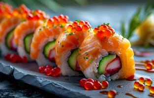 Sushi rolls on a slate plate. Colorful sushi rolls with salmon, cucumber, and fish roe are beautifully plated on a slate surface. photo