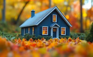 Miniature blue house among autumn leaves. A small blue house stands surrounded by vibrant orange and yellow autumn leaves, creating a peaceful autumnal setting. photo