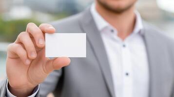 Business professional holds blank card outdoors in urban setting during daytime to signify networking opportunities photo