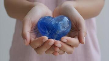 Holding a blue heart-shaped crystal in hands while standing in a soft light indoor setting photo