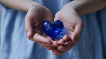 Hands gently cradle a vibrant blue heart symbolizing love and compassion in a soft-lit setting photo