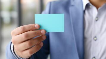 Individual holds a blank business card in a professional setting during a networking event photo