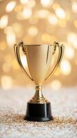 A shiny gold trophy with a trophy's base sits on a smooth surface. The background is a warm beige color, black the enhancing gleam. Coins are scattered around the base. photo