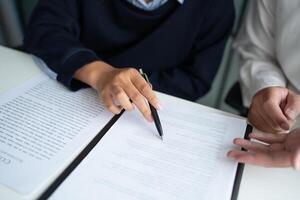 two people signing a document on a table photo