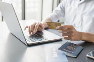 man using laptop and credit card to pay for online ticket photo
