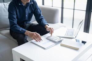 a man sitting on a couch with a laptop and a calculator photo