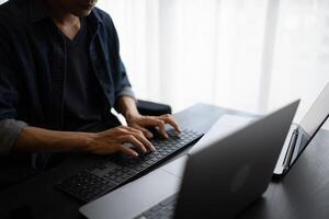 Asian man software engineer Working on Computer for writing program code Software Engineer finding errors tech support devops creating digital photo