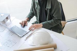 man in a green jacket sitting at a table with a laptop photo