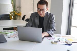 a man in a suit sitting at a table with a laptop photo