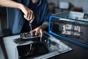 a man is fixing a computer with a screwdriver photo