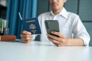 man holding passport and smartphone at desk photo