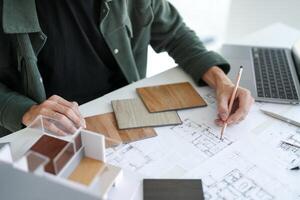 a man is working on a project with blueprints and a laptop photo