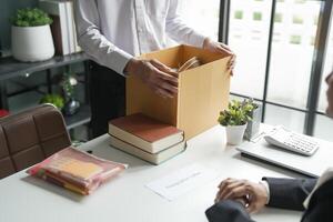 Business man sending resignation letter and packing Stuff Resign Depress or carrying business cardboard box Change of job or fired from company resign. photo