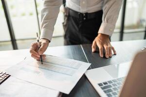 Close up of businessman hands signing or writing document paperwork and report Auditor analysis making notes with Business Document. photo