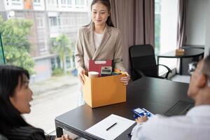 Quit Job asian businesswoman sending resignation letter and packing Stuff or carrying business cardboard box in office. Change of job or fired from company photo