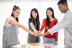 group of people Asian business hands stack unity and support Team fold their hands on each other photo