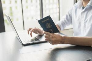 man using laptop and passport in office photo