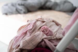 Messy pile of clothes on chair in unkempt bedroom. Clutter and household disorder in an untidy and lived-in space photo