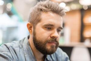 Thoughtful man with beard in casual setting looks down in silence. Quiet introspection and emotional presence in everyday life. photo