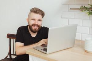 Happy smiling young man watching and working on computer laptop at home. Technologies, remote work photo