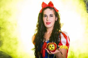 Female dressed as fairytale character holds Radioactive atomic nuclear ionizing radiation danger warning symbol on apple. Nuclear and radiation photo