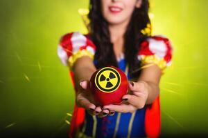 Woman dressed as Snow White holds Radioactive atomic nuclear ionizing radiation danger warning symbol on apple. Nuclear concept. photo