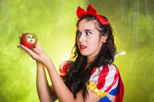 Scary Woman dressed as fairytale character holds Radioactive atomic nuclear ionizing radiation danger warning symbol on apple. Nuclear and radiation measurement concept. photo