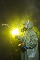 Radiation, pollution and danger concept - Man in protective clothing and a gas mask on dark background photo