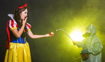 Scared Woman dressed as fairytale character holds Radioactive atomic nuclear ionizing radiation danger warning symbol on apple. Nuclear and radiation measurement concept. photo