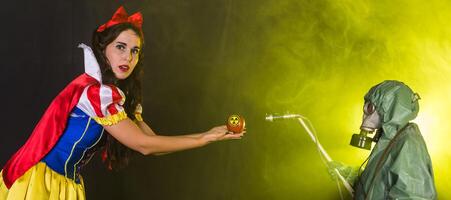 Woman dressed as fairytale character holds Radioactive atomic nuclear ionizing radiation danger warning symbol on apple. Nuclear and radiation measurement photo