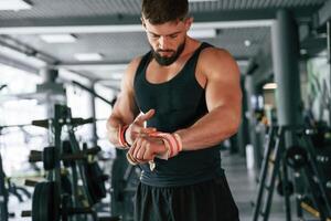 Red protective bandages on hands. Strong muscular man is working out in the gym photo