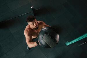 Top, view,,, throwing the fitness ball. Strong muscular man is working out in the gym photo