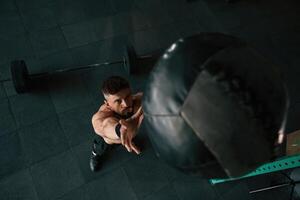 Top view, throwing ,the ,,fitness ball. Strong muscular man is working out in the gym photo