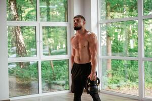 Standing, holding dumbbells,.. Strong muscular man is working out in the gym photo