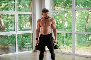 With heavy ,dumbbells.. Strong muscular man is working out in the gym photo