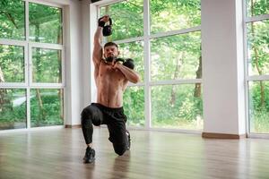 Against ,the ,windows. With dumbbells. Strong muscular man is working out in the gym photo