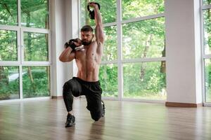 Against the, windows.. With dumbbells. Strong muscular man is working out in the gym photo