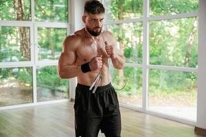 With jumping rope. Strong muscular man is working out in the gym photo