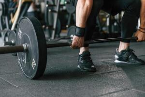 Big ,and, heavy barbell in hands. Strong muscular man is working out in the gym photo