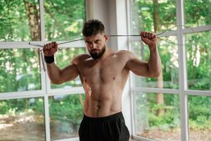 Holding ,jump, rope. Strong muscular man is working out in the gym photo