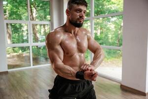 Daytime, ,trees outside the windows. Strong muscular man is working out in the gym photo