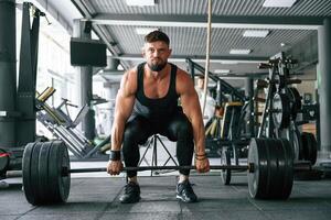 Lifts, a barbell. Strong ,,muscular man is working out in the gym photo