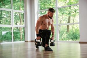 Standing,, holding dumbbells. Strong muscular man is working out in the gym photo