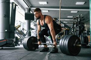 Lifts, a barbell. Strong muscular man is working out in the gym photo