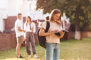 Girl is with digital tablet... Group of students are outside together photo