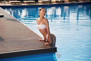 Positive, vibes. Beautiful woman in,, bikini is resting by the pool photo