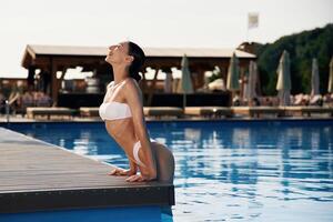 Positive, vibes. Beautiful woman, in bikini is resting by the pool photo